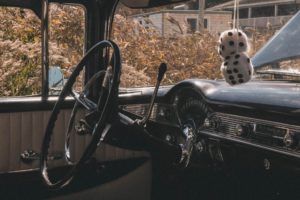 des dés en peluche accrochés au rétroviseur d'une voiture ancienne - Photo by Joe Mannarino on Unsplash