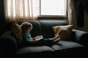petite fille lisant la Bible assise sur un canapé - Photo by Josh Applegate on Unsplash