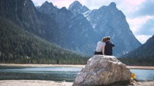 un couple assis sur un rocher devant un lac de montagnes - Photo by Timo Stern on Unsplash