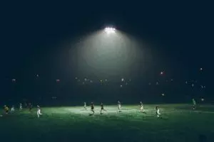 une partie de foot en soirée, sou sle feux des lampes - Photo by Abigail Keenan on Unsplash
