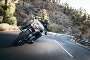 un homme en grosse moto roulant vite dans un virage, venent vers nous - Photo by Harley-Davidson on Unsplash