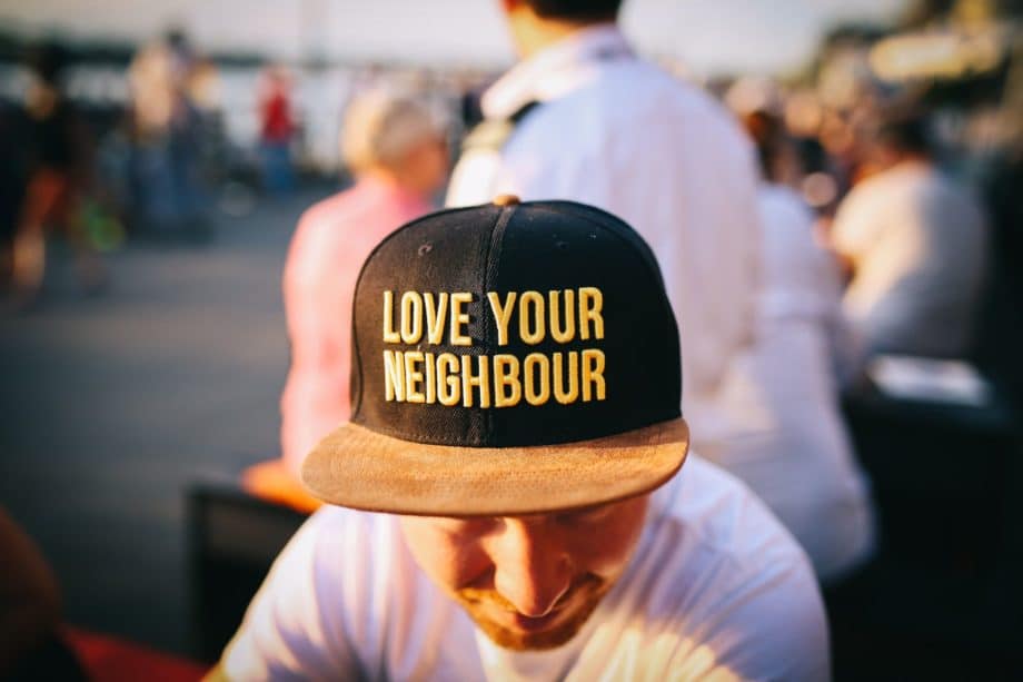 Un homme avec une casquette où est marqué en gros "Aime ton prochain" - Photo by Nina Strehl on https://unsplash.com/fr/photos/Ds0ZIA5gzc4