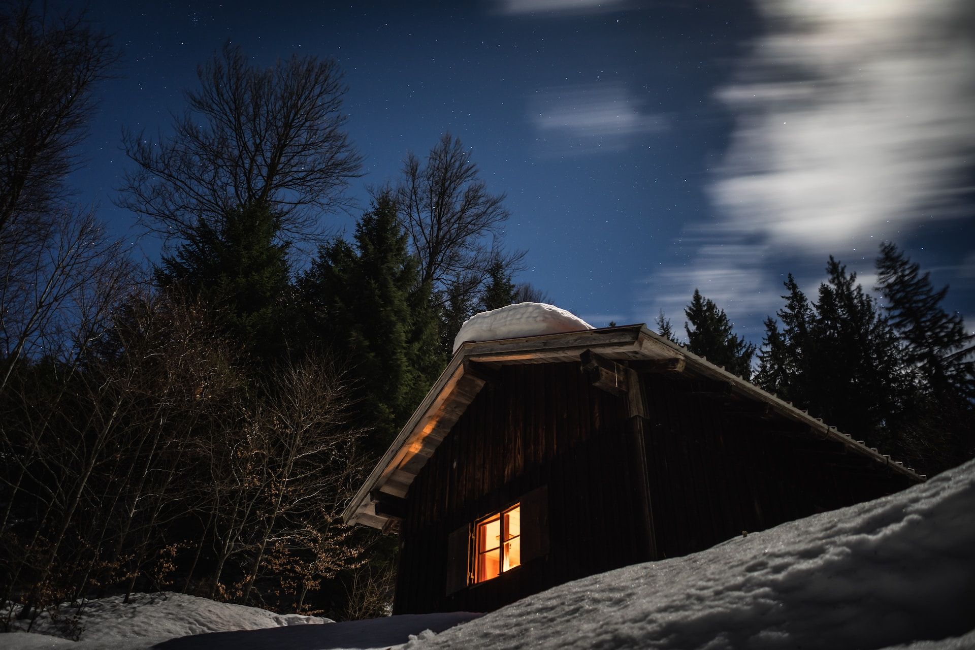un chalet avec fenêtre allumée dans la nuit d'hiver - Photo by Patrick Schneider on https://unsplash.com/fr/photos/D_7_Ip4AY40