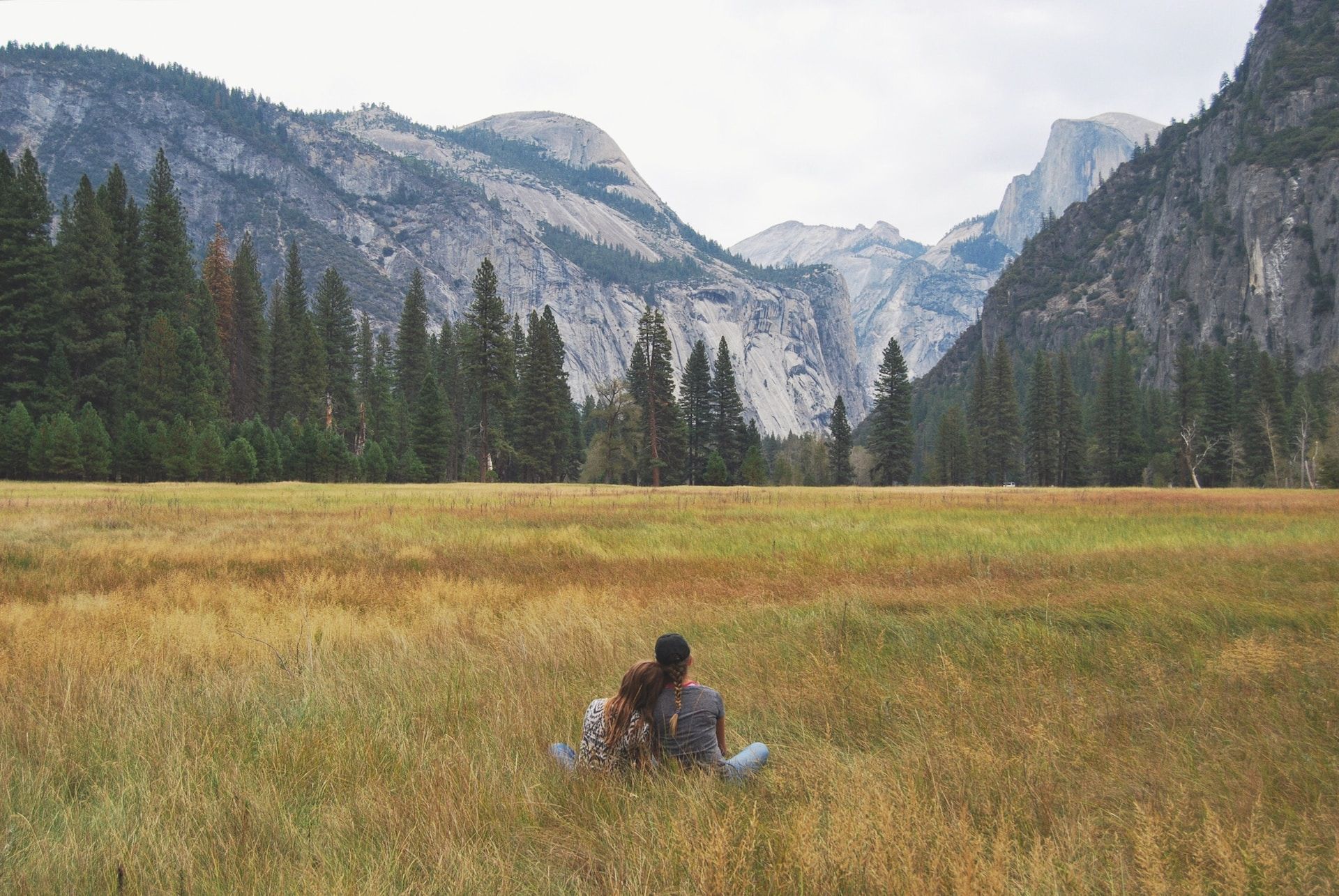 couple assis dans l'herbe devant des montagnes (yosemite) - Photo by Anneliese Phillips on https://unsplash.com/fr/photos/uv4-vl3liKM