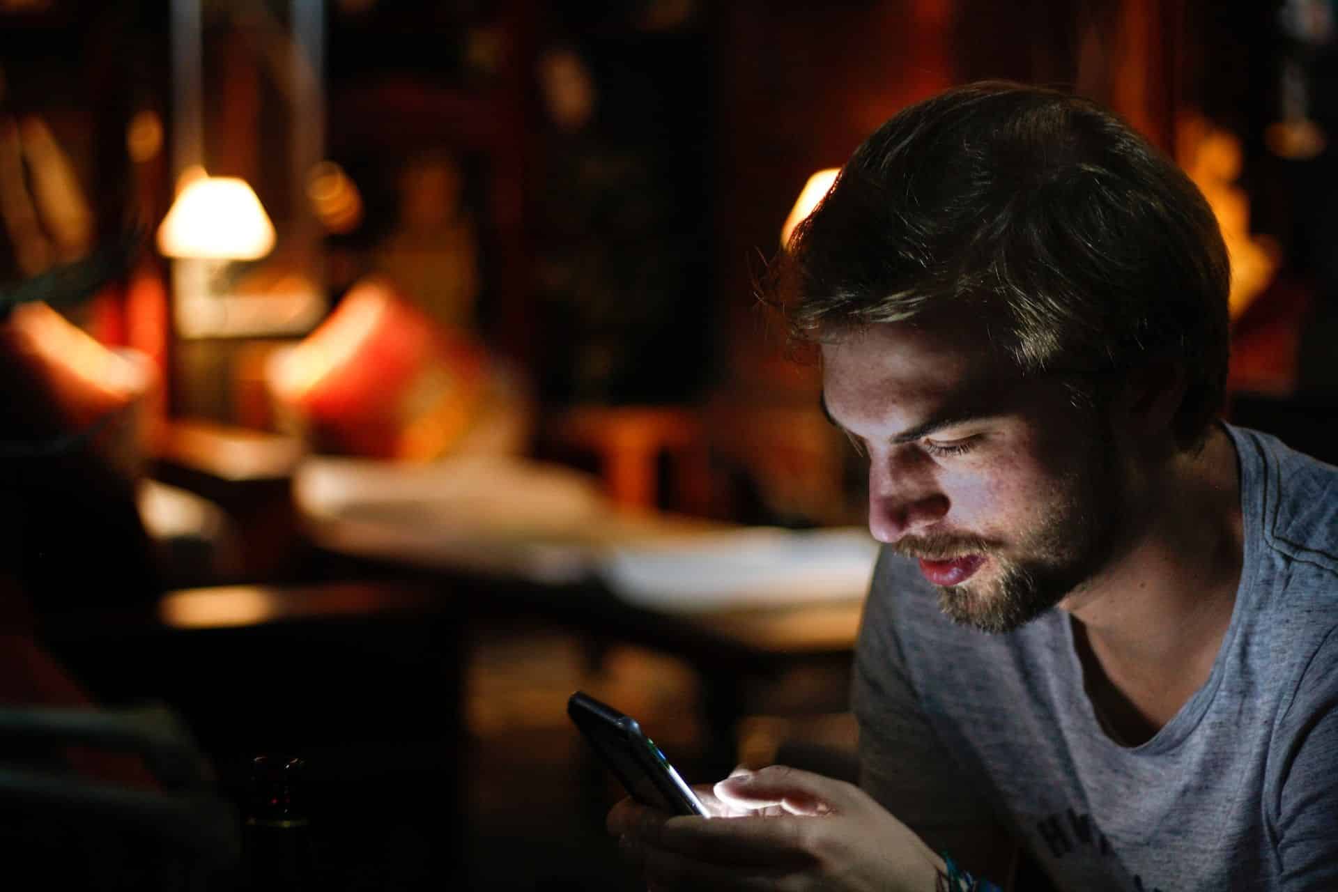 jeune homme barbu regardant son téléphone de chez lui - Photo by Eddy Billard on https://unsplash.com/photos/M5UD_FyuDl8