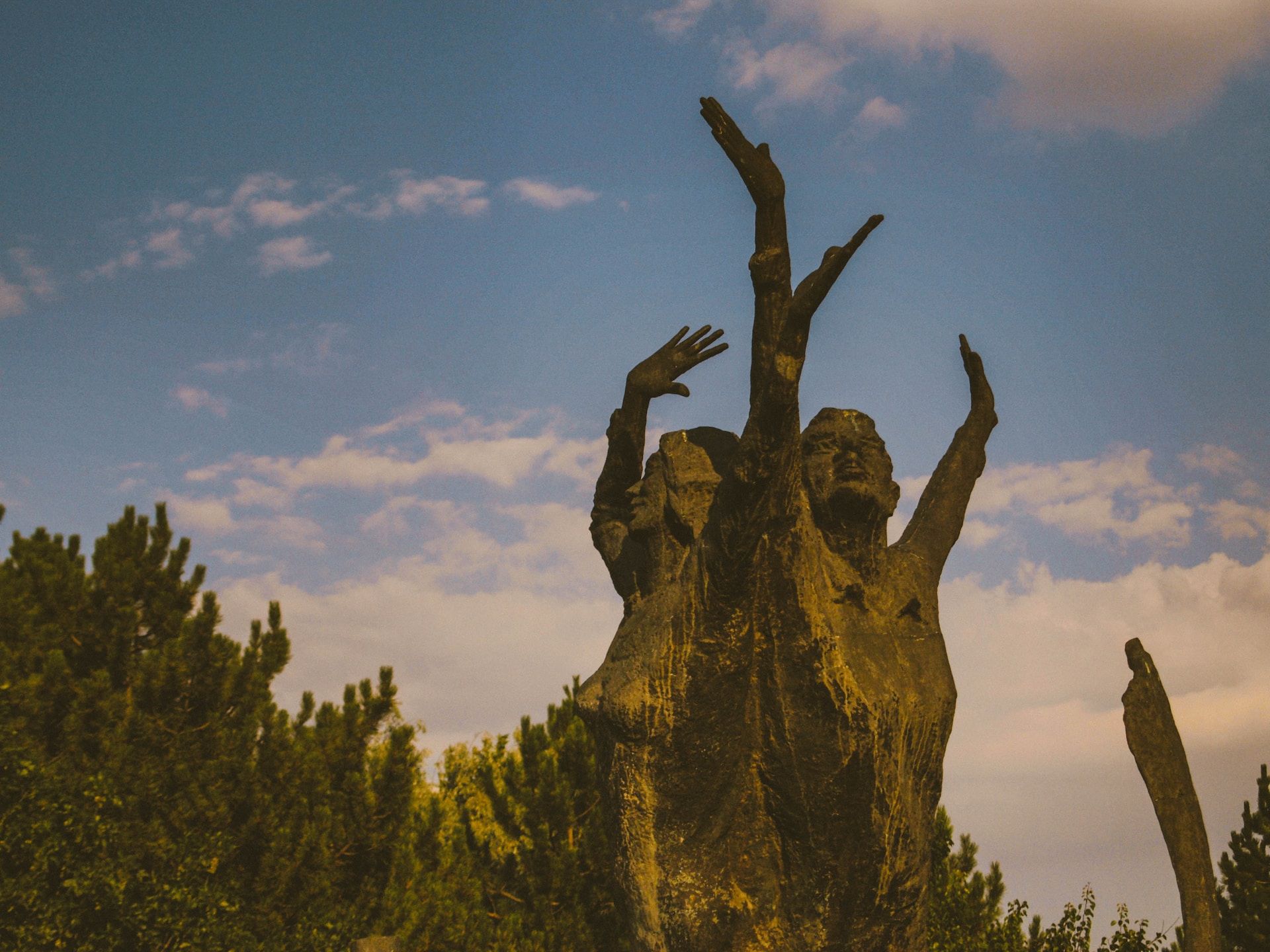 étrange sculpture de deux personnes levant les bras au ciel dans la forêt - Photo by Ramazan Tokay on https://unsplash.com/photos/8Mv47i4a6UI