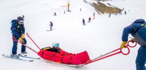 Deux pisteurs secouristes portent secours à un enfant blessé - Photo de Ed Wingate sur https://unsplash.com/fr/photos/une-patrouille-de-ski-sauve-un-skieur-blesse-sur-un-traineau-YgNero3ER0I