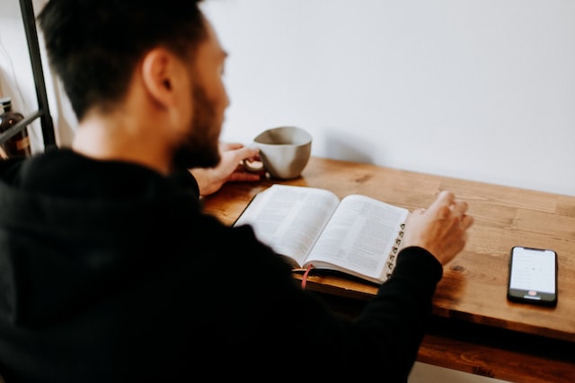 Un homme lit sa Bible en buvant son café - Photo by Priscilla Du Preez on https://unsplash.com/photos/SSh9O_-sTzg