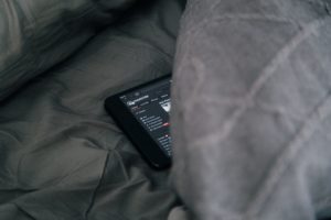 téléphone allumé sur un site pornographique, posédans un lit avec des draps gris foncés - Photo by charlesdeluvio on https://unsplash.com/photos/UuIHPyGjCAM 