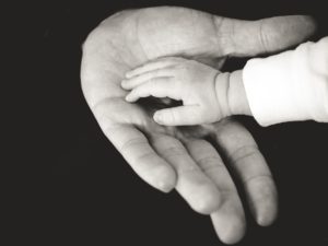 Une main de bébé dans la main d'un homme - Photo by Liane Metzler on https://unsplash.com/photos/B32qg6Ua34Y 