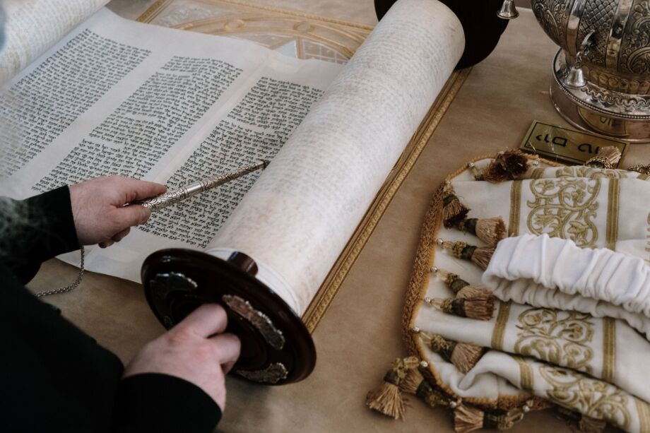 Une personne lit un rouleau de la Bible hébraïque - photo par cottonbro studio sur https://www.pexels.com/photo/person-holding-black-and-white-tube-5986499/