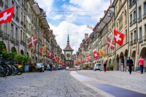 la rue principale à Berne, avec des drapeaux suisses - Photo de Alin Andersen sur https://unsplash.com/fr/photos/qf4fhNnsn6M 