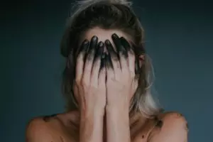 femme avec les mains pleines d'encre noire se prend le visage - Photo de Jacqueline Day sur https://unsplash.com/fr/photos/krUUaZ4GvHk 