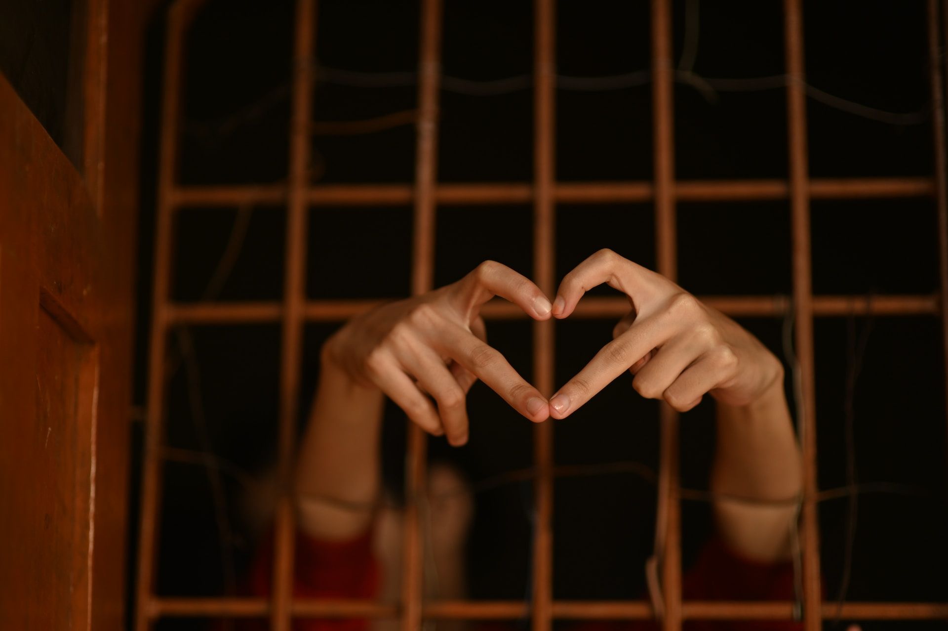 un prisonnier fait un cœur avec ses doigts derrière les barreaux - Photo de Rajesh Rajput sur https://unsplash.com/fr/photos/Sw8LdXgIsUY