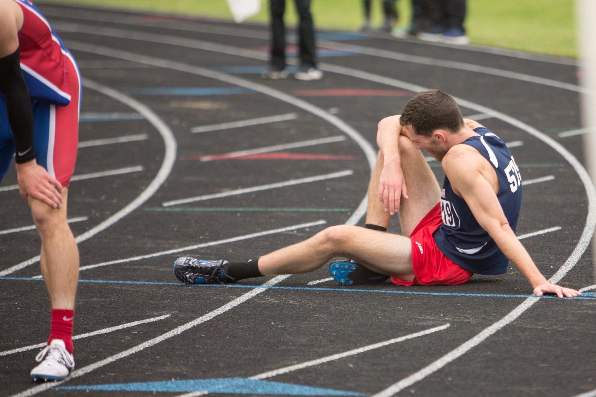 un athlète est assis, épuisé dans une piste de course à pied - Photo de Elisa Kennemer sur https://unsplash.com/fr/photos/OHmYjiiaOvs