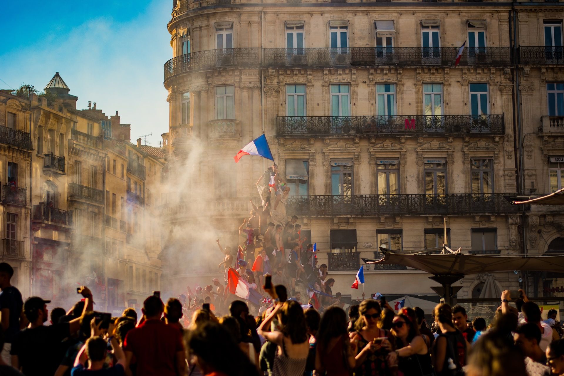Une manifestation en France avec une foule grimpant sur une statue avec un drapeau - Photo de Pierre Herman sur https://unsplash.com/fr/photos/Fw_2kaQZc90