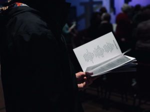 une personne tient un feuillet de culte avec les paroles du cantique - Photo de Tyler Callahan sur https://unsplash.com/fr/photos/NEK0tBmYjqA