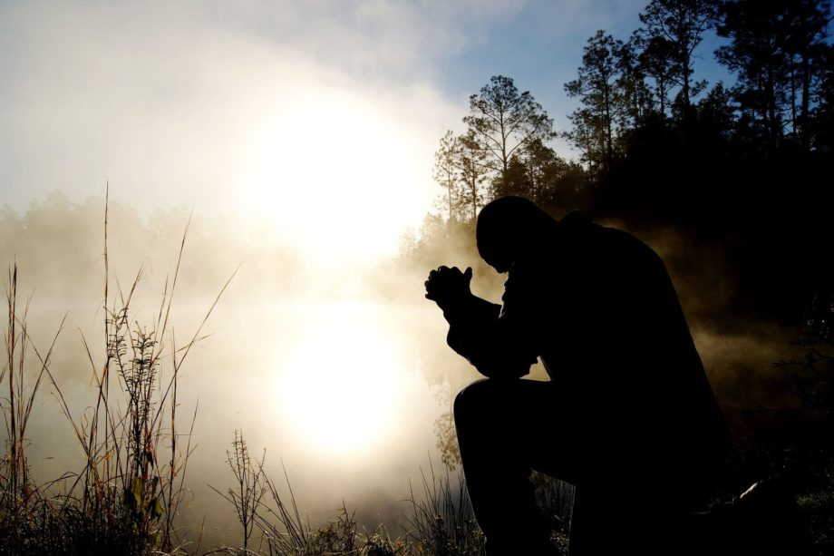 Un homme assis, en prière, devant un lac à l