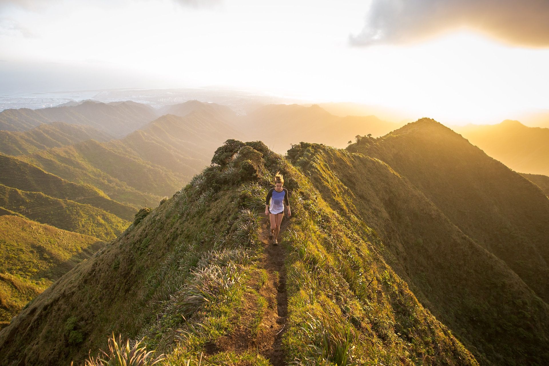 Une jeune femme marche sur un chemin de crête, en montagne, au lever du soleil - Photo de Kalen Emsley sur https://unsplash.com/fr/photos/7bwQXzbF6KE