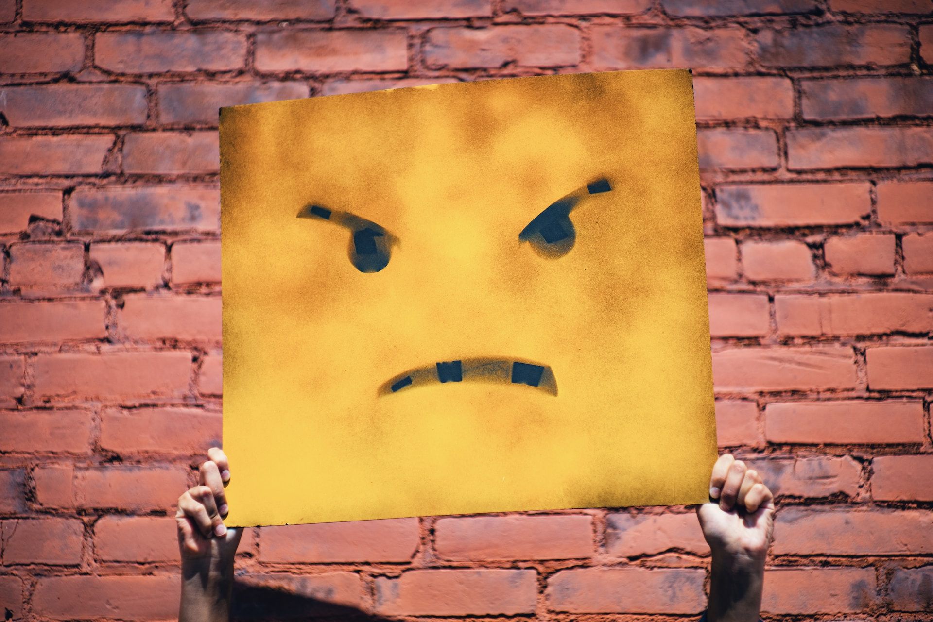 Un panneau tenu à bout de bras portant une icône de colère - Photo de Andre Hunter sur https://unsplash.com/fr/photos/5otlbgWJlLs