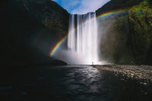 large cascade avec un arc en ciel et une toute petite personne devant - Photo de Sorasak sur https://unsplash.com/fr/photos/8ZAxI5FwjFo 