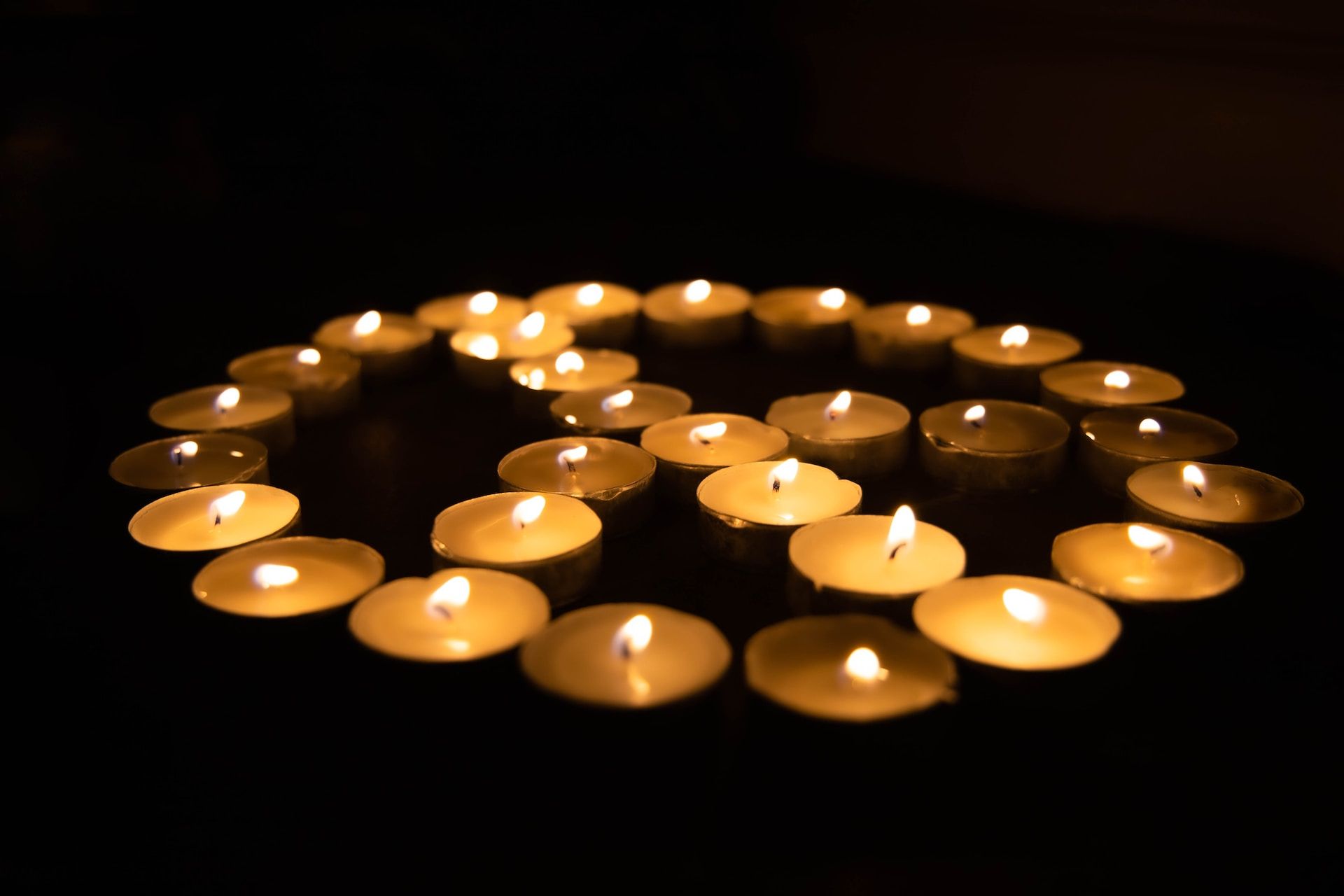 Un signe de paix dessiné avec des petites bougies allumées dan sle noir - Photo de Joshua Sukoff sur https://unsplash.com/fr/photos/SsphTEregQ8