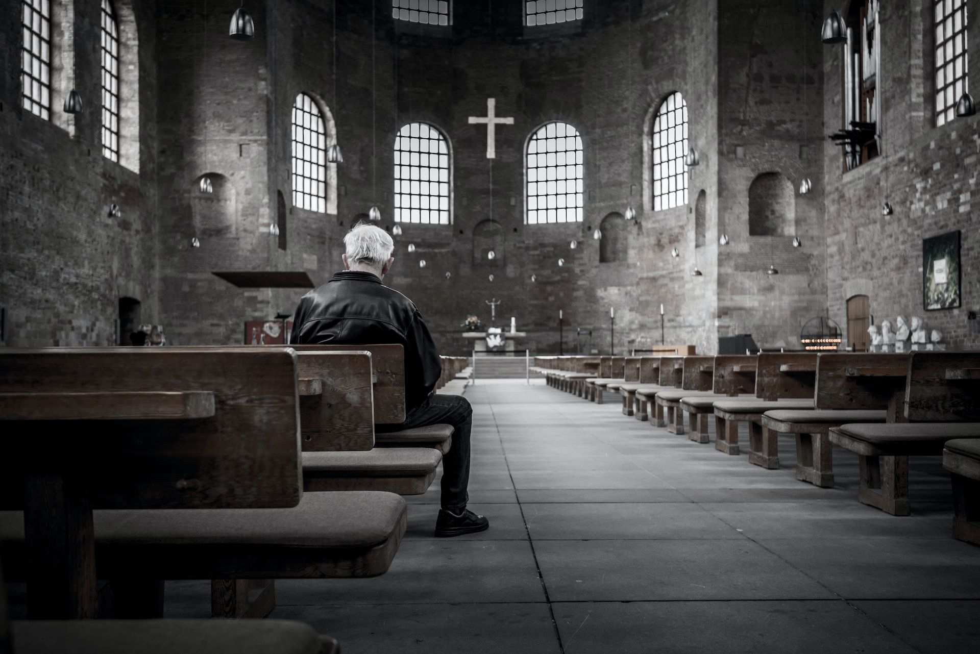 Une église grisâtre avec un homme âgé et seul assis dedans - Photo de Stefan Kunze sur https://unsplash.com/fr/photos/personne-assise-sur-un-banc-a-linterieur-de-leglise-oLdm7mnhDic