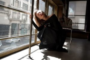 Une femme accroupie se tord le cou pour voir vers le haut par la fenêtre - Photo de Anastasiya Badun sur https://unsplash.com/fr/photos/une-femme-en-robe-noire-appuyee-contre-une-fenetre-y_HAunqz4CM