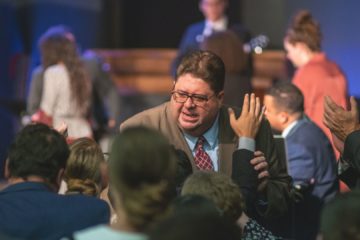 Un pasteur dans une assemblée évangélique - Photo de Geron Dison sur https://unsplash.com/fr/photos/uomo-in-giacca-nera-che-indossa-occhiali-da-vista-RRqkvfM-loU