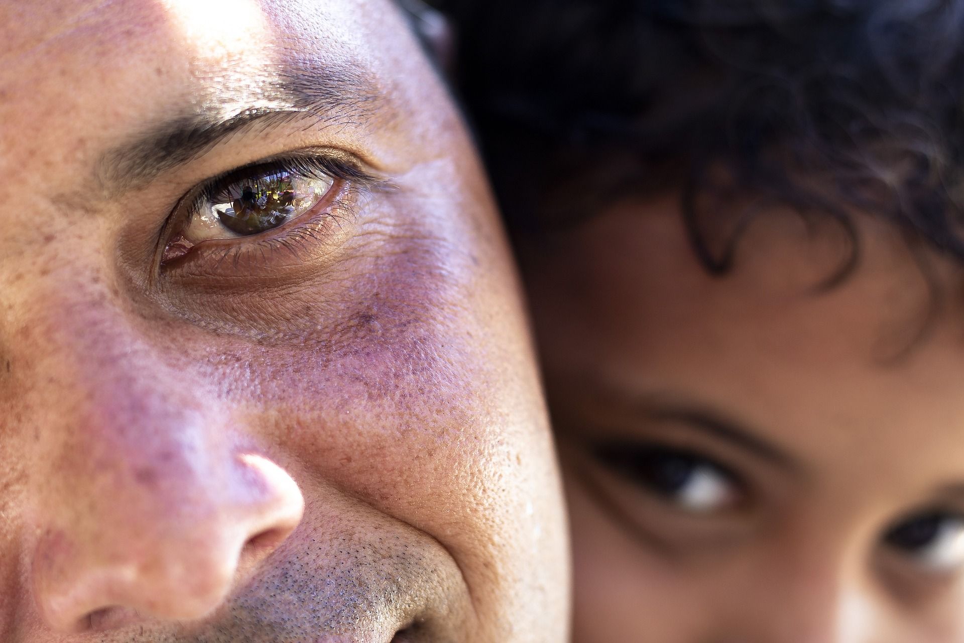 Le regard d'un père, sincèrement ému, et derrière lui le regard de son fils - Image par willypp de https://pixabay.com/fr/photos/portrait-p%C3%A8re-fils-les-yeux-enfant-5483735/