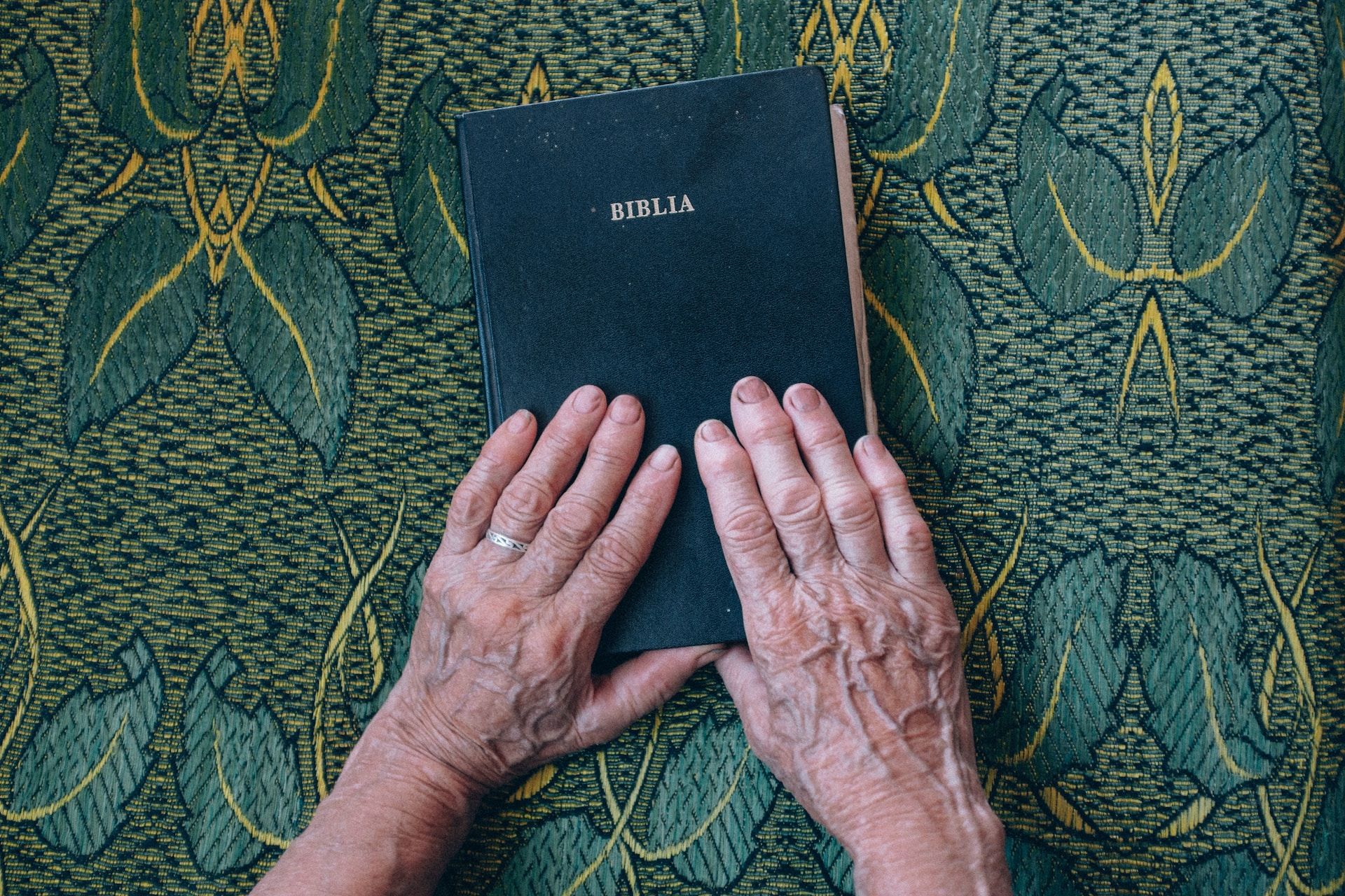 les mains d'une femme âgée posées sur une bible fermée - Photo de Raul Petri sur Unsplash