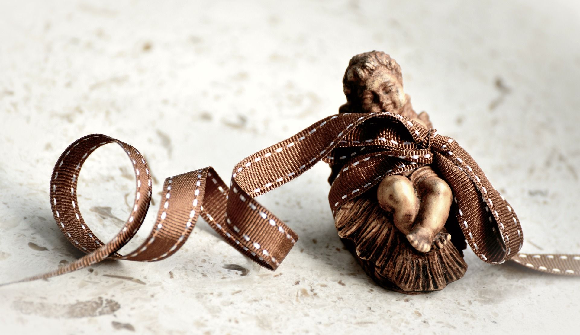 Jésus dans la crèche figuré par un santon emballé d'un bolduc - Image par congerdesign de https://pixabay.com/fr/photos/no%C3%ABl-conte-de-no%C3%ABl-bible-3701985/