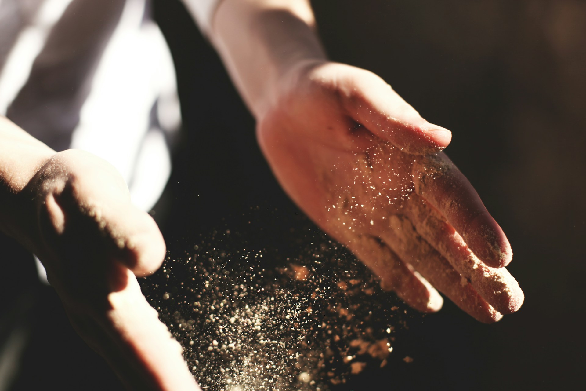 Deux mains pleines de farine qui vole dans l'air, tout en pétrissant de la farine et du levain pour faire du pain - Photo de Austin Ban sur https://unsplash.com/fr/photos/main-dune-personne-avec-de-la-poussiere-pendant-la-journee-IS6RwpuEJpY
