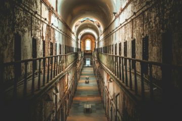 Une prison abandonnée, vide et en ruine - Photo de Lance Anderson sur https://unsplash.com/fr/photos/un-long-couloir-avec-de-nombreuses-portes-UDT5em_-lUk
