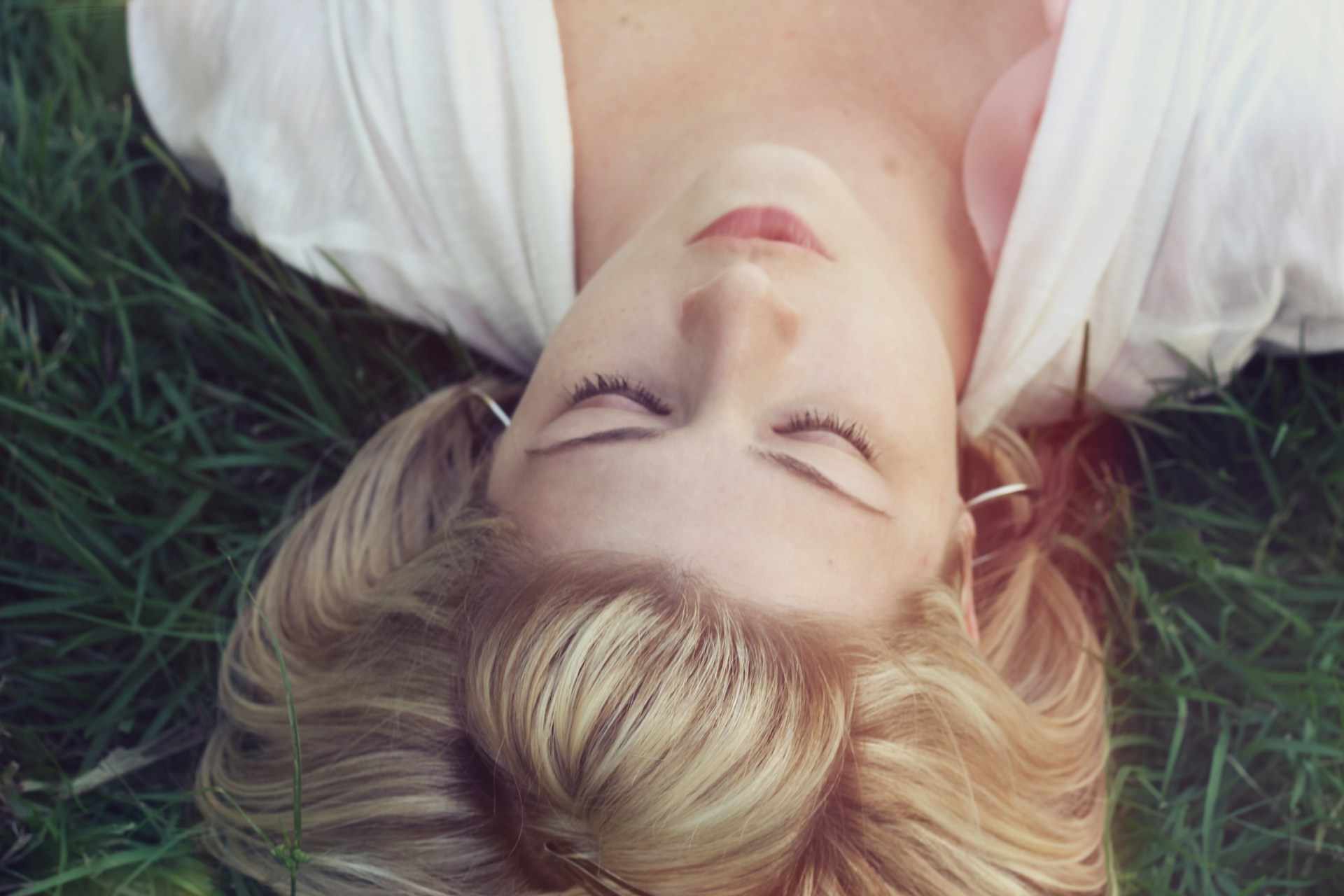 Vue de haut de la tête d'une jeune femme blonde dormant dans l'herbe - Photo de Jacob Townsend sur https://unsplash.com/fr/photos/femme-couchee-sur-des-herbes-vertes-OdvNB15f7Uo