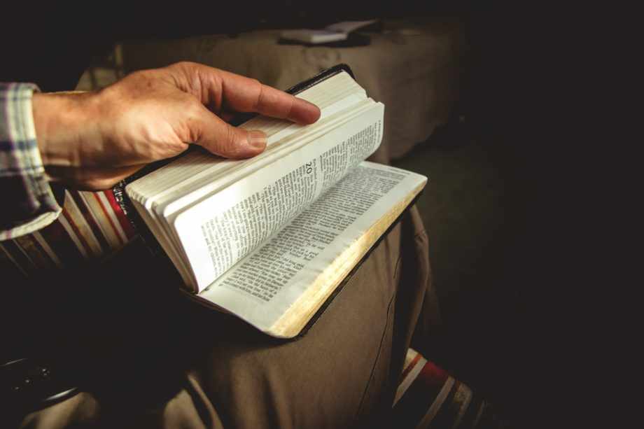 Une main dhome tourne les pages d'une Bible posée sur ses genoux - Photo de James Coleman sur https://unsplash.com/fr/photos/personne-tenant-un-livre-z0LhIrvtRoU