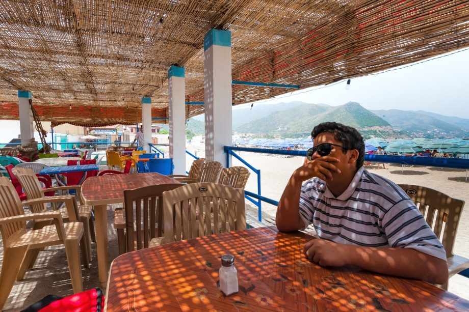 Un homme attablé au café de la plage à Bejaia en Algérie - Image par Loyloy Thal de https://pixabay.com/fr/photos/caf%C3%A9-plage-boulimat-bejaia-alg%C3%A9rie-2437917/
