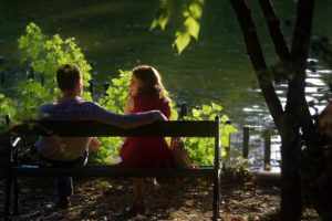 Photo en contre jour d'un couple sur un bac face à un lac - Image par Mircea Iancu de https://pixabay.com/fr/photos/coupler-banc-content-lac-date-4453726/