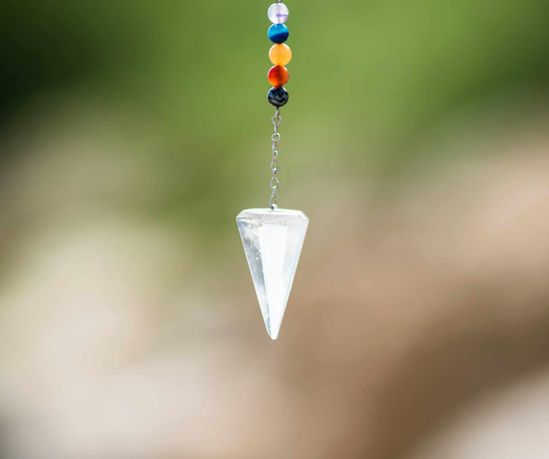 Un pendule en cristal de roche, censé nous guider - Photo de Frames For Your Heart sur https://unsplash.com/fr/photos/pendentif-diamant-argent-avec-perles-rouges-bleues-et-jaunes-Z4Dtkci_Enk