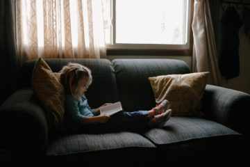 Une fillette lit la Bible allongée sur un canapé Image par StockSnap de https://pixabay.com/fr/photos/enfant-gens-fille-s%C3%A9ance-canap%C3%A9-2603857/