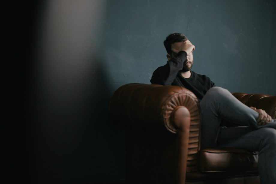Un homme barbu assis sur le fauteuil se prend le visage avec sa main, l'air inquiet - Photo de Nik Shuliahin 💛💙 sur https://unsplash.com/fr/photos/un-homme-se-tient-la-tete-alors-quil-est-assis-sur-un-canape-BuNWp1bL0nc