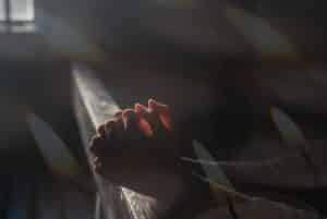 deux mains croisées en prière, dans une église sombre, éclairée par une petite fenêtre - Image par Ri Butov de https://pixabay.com/fr/photos/pri%C3%A8re-foi-religion-esp%C3%A9rer-6764197/