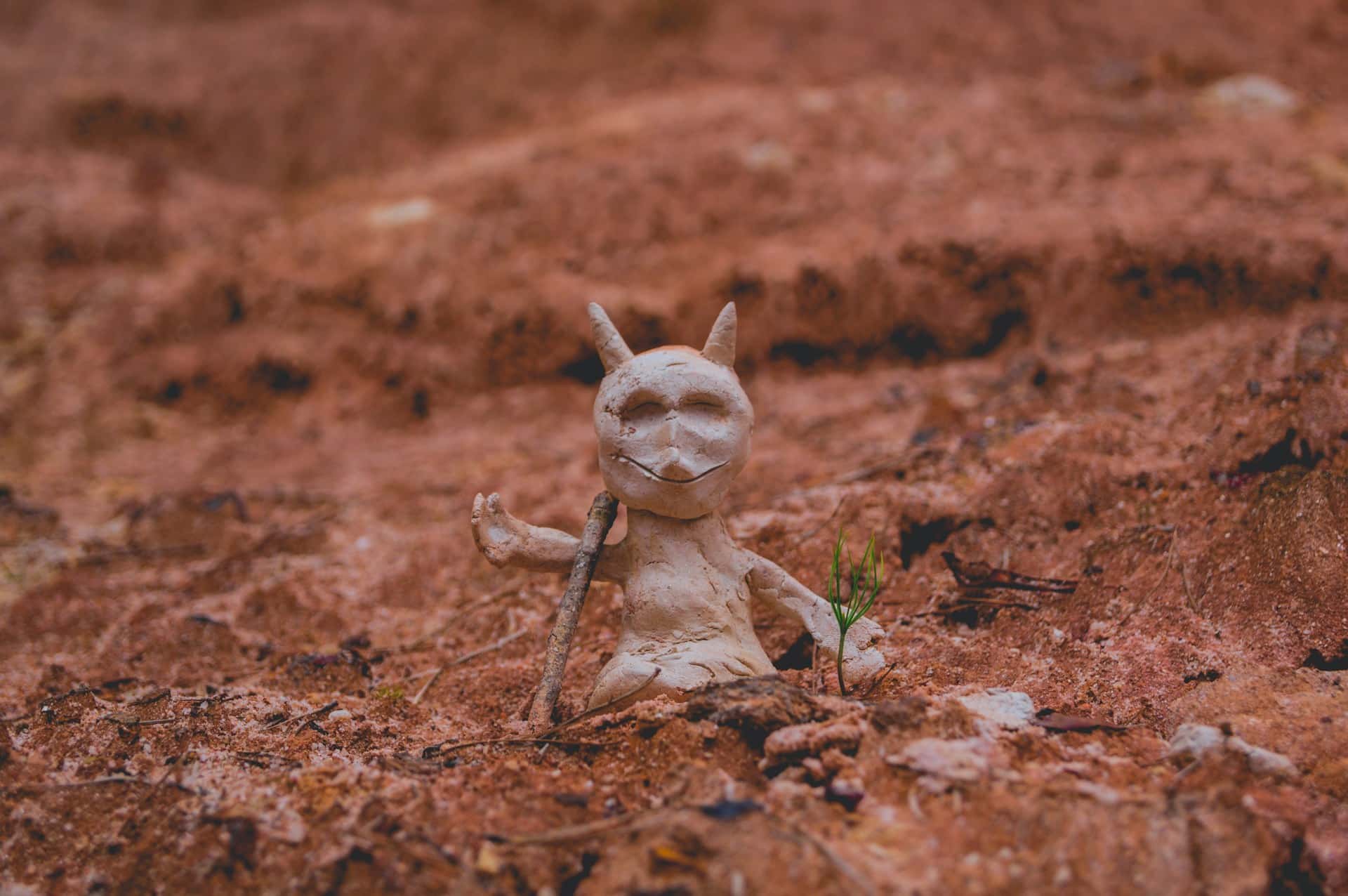 petite sculpture d'un diable en terre posé sur le sol - Photo de Timothy Dykes sur https://unsplash.com/fr/photos/figure-blanche-a-cote-de-la-plante-verte-KTYSVnv6lUw