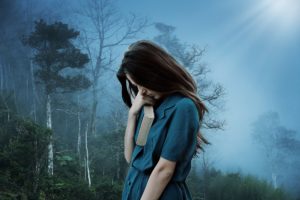 femme mystérieuse et triste, le visage caché par ses longs cheveux et tenant un gros livre sur fond de nature brumeuse - Image par Enrique Meseguer de https://pixabay.com/fr/photos/fille-tristesse-solitude-triste-3421489/