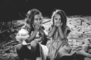 Photo de deux petites filles riant ensemble - Photo de Caroline Hernandez sur https://unsplash.com/fr/photos/photographie-en-niveaux-de-gris-de-deux-filles-fermant-la-bouche-tJHU4mGSLz4