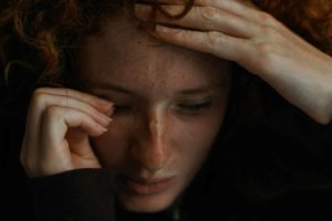 Visage d'une femme qui pleure, avec ses mains, sur fond sombre - Photo de Tom Caillarec sur https://unsplash.com/fr/photos/un-gros-plan-dune-personne-tenant-sa-tete--0qyaihQxUU