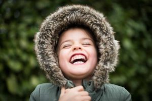 un enfant avec une capuche de parka en train de rire - Photo de S&B Vonlanthen sur https://unsplash.com/fr/photos/photographie-selective-de-mise-au-point-denfant-riant-FaiZNiofP-U