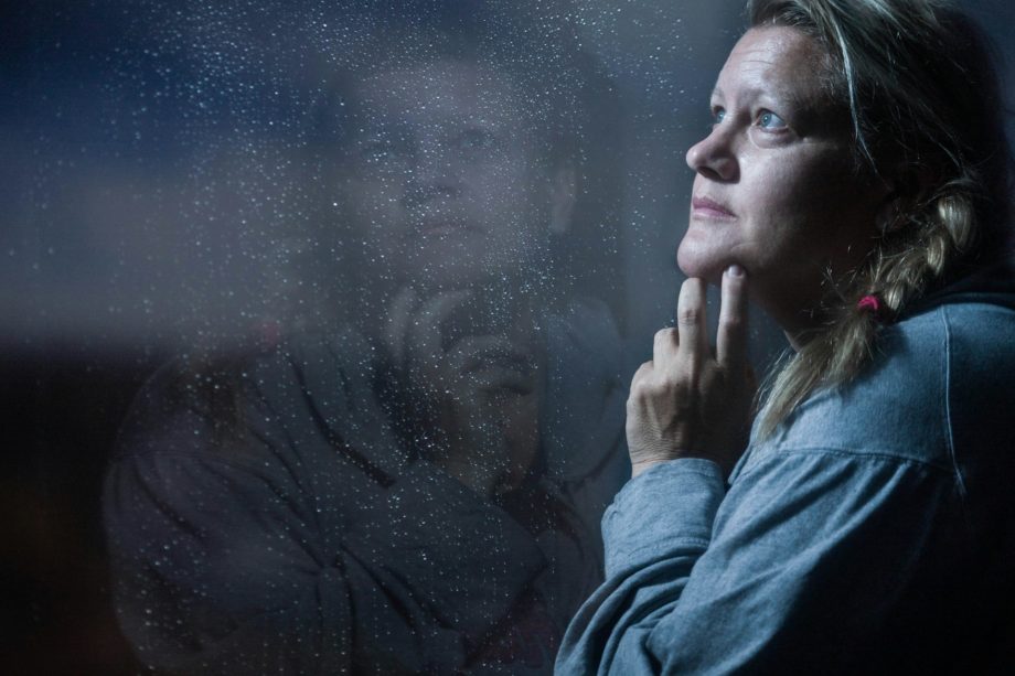 Une femme d'age moyen regarde avec tristesse vers le haut - Photo de Cheron James sur https://unsplash.com/fr/photos/clear-glass-window-panel-casting-reflection-of-woman-touching-her-jaw-jxNOPmh-wbQ