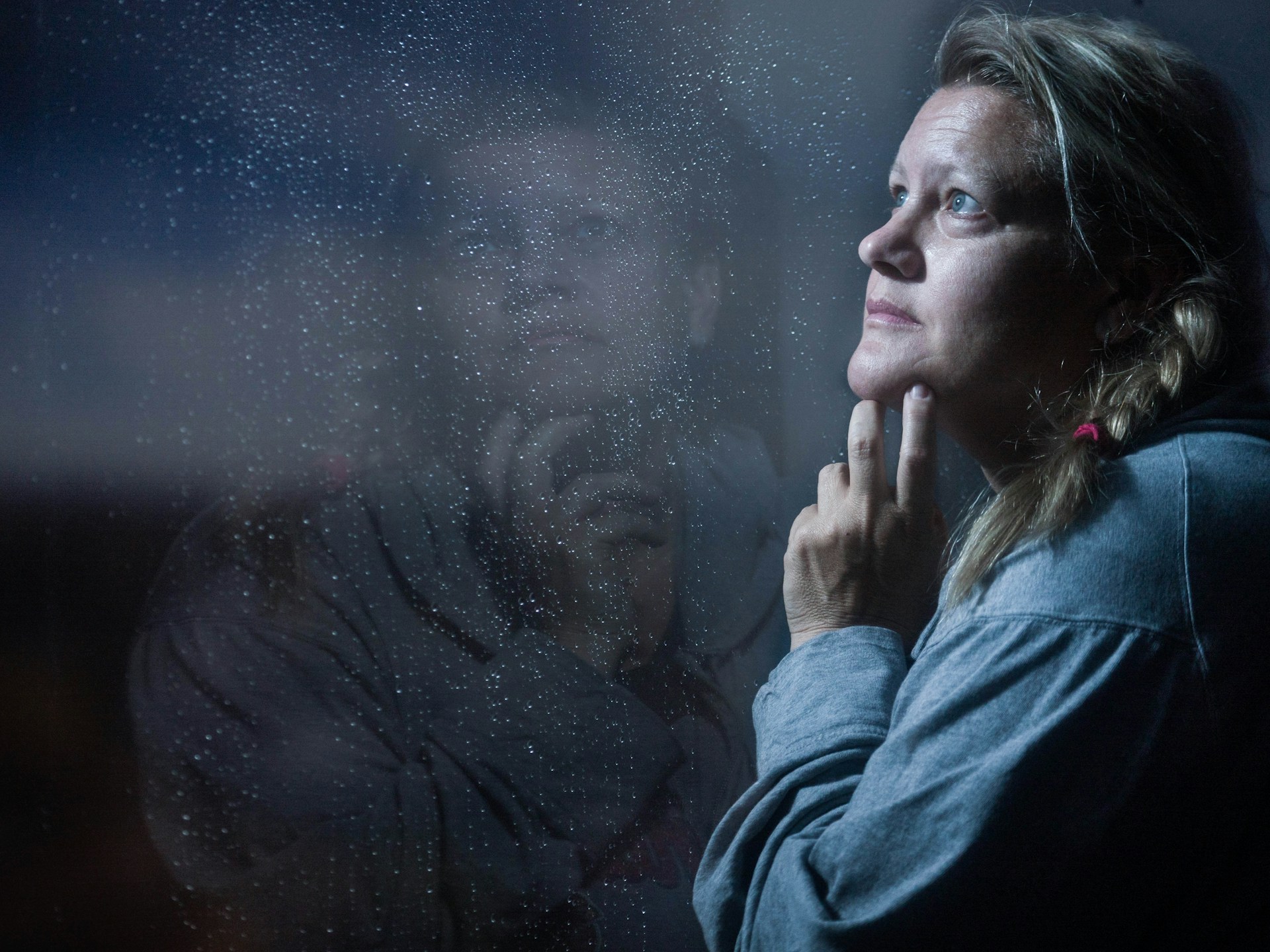 Une femme d'age moyen regarde avec tristesse vers le haut - Photo de Cheron James sur https://unsplash.com/fr/photos/clear-glass-window-panel-casting-reflection-of-woman-touching-her-jaw-jxNOPmh-wbQ