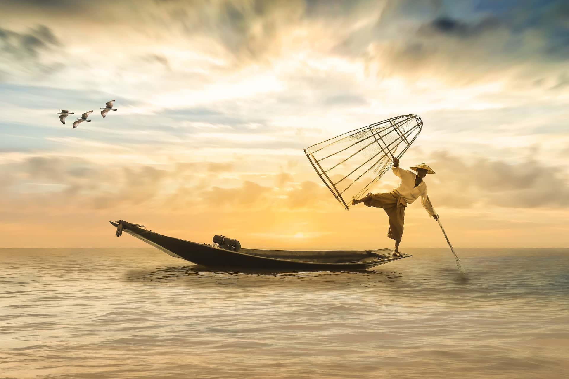 Un pêcheur dans une position acrobatique sur sa barque, au coucher du soleil, en Asie - Image par Myriams-Fotos de https://pixabay.com/fr/photos/p%C3%AAcheur-bateau-de-p%C3%AAche-bateau-2739115/